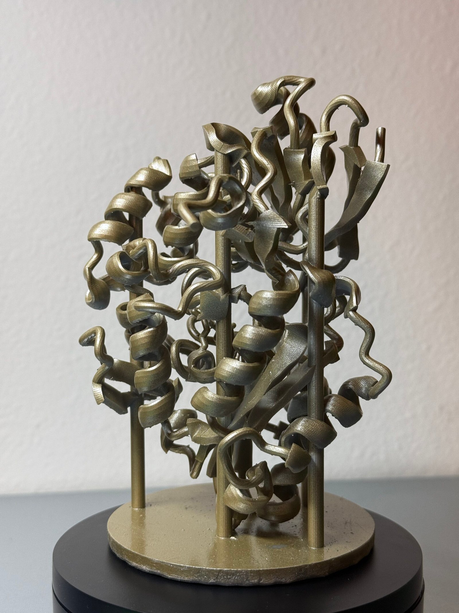 A gold 3D printed sculpture of a cartoon protein model